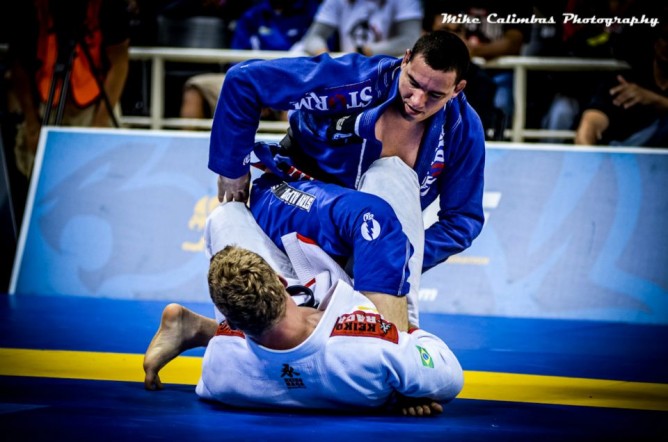 Two athletes in a judo match on a blue mat with spectators in the background.