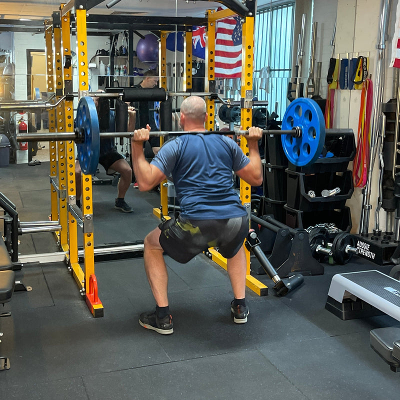 Person performing squats with a barbell in a gym setting