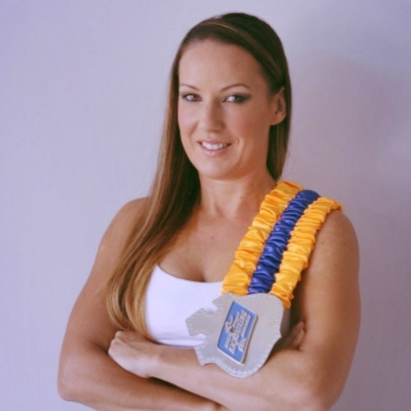 Woman wearing a yellow and blue sash with a medal around her neck against a plain background