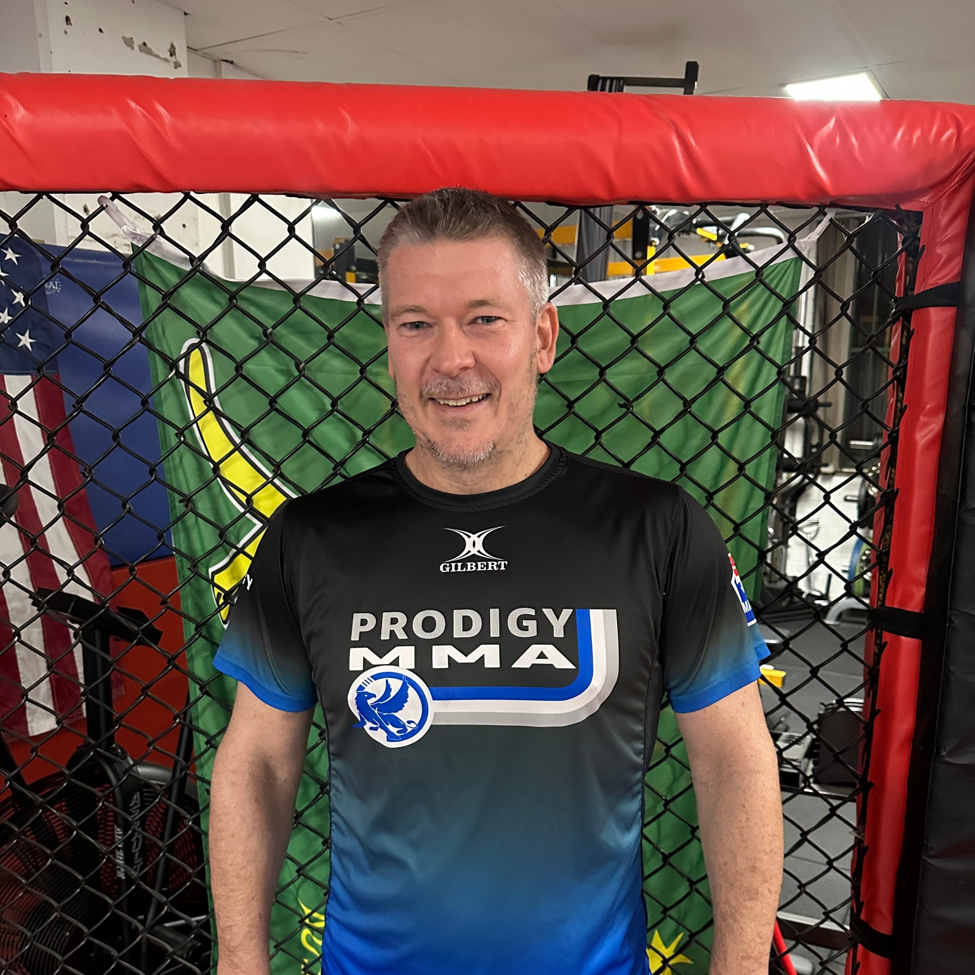 Man posing in a boxing ring with a branded shirt